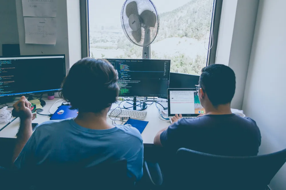 Two developers working together on a project – symbol for DevOps collaboration